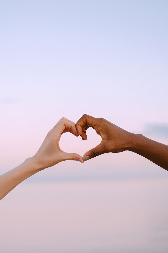 Two hands forming a heart shape with fingers, symbolizing care and support