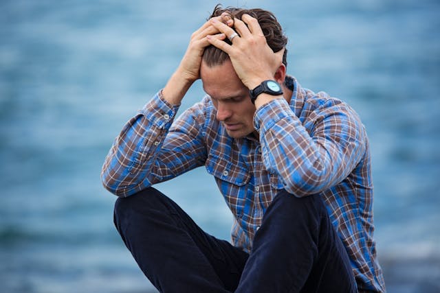 Man sitting with head in hands, showing distress or sadness