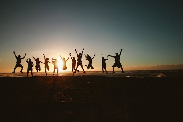 Silhouettes of friends jumping together at sunset, representing hope and community